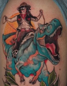 Colorful cowgirl riding dinosaur tattoo by Lisset Raven Cabrera at Legendary Tattoos in Las Vegas, Nevada.