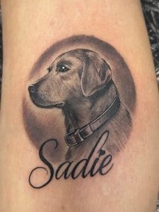 A black and grey portrait of the side of a dog head, with the name Sadie below.