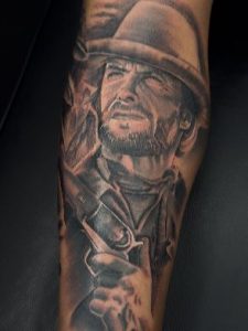 A portrait of Clint Eastwood from one of his famous western movies, holding a gun.